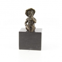 A bronze statue/sculpture of a small, seated girl