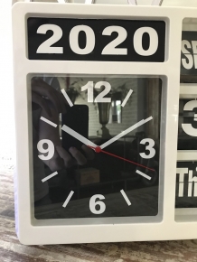 Eine Uhr mit Jahr, Datum und Uhrzeit, mit Ständer, kann aber auch an die Wand gehängt werden, weiß