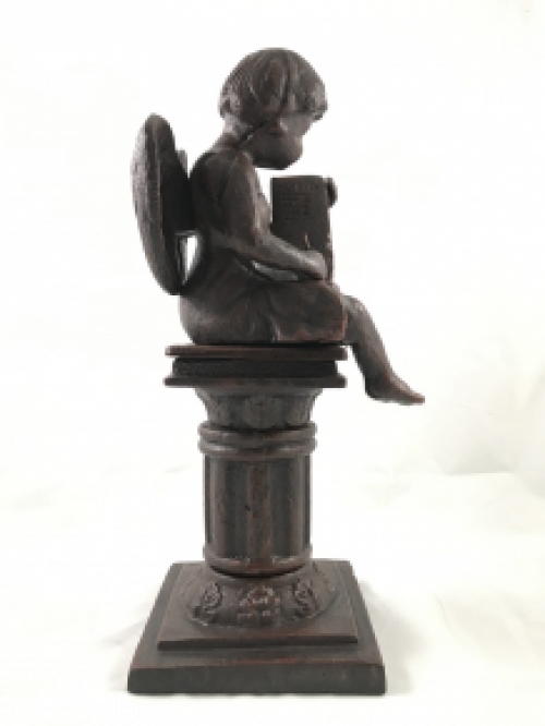 Intact statue of an angel sitting on a pedestal writing, cast iron