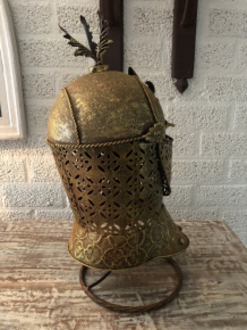 A beautiful metal brass knight helmet on stand.