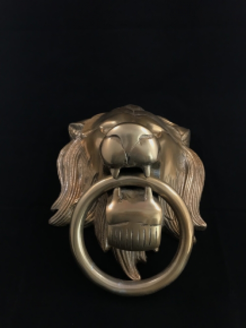 A lion's head, made of aluminum in a brass color, as a door knocker